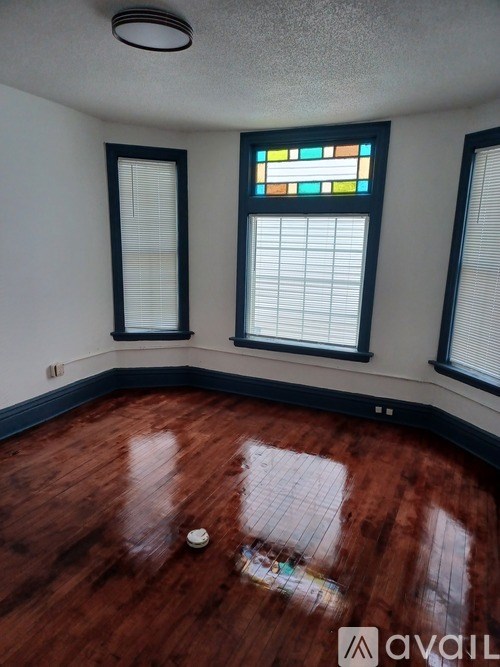 A room with a wooden floor and a stained glass window.