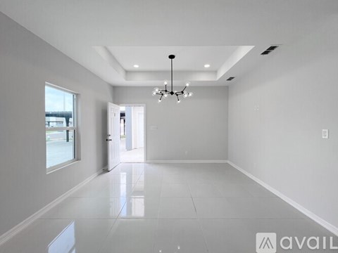 A spacious, empty room with a chandelier and a large window.