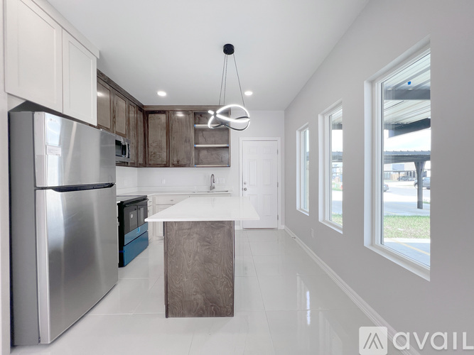 A modern kitchen with a stainless steel refrigerator and a white island.