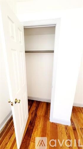 A white door with a gold handle is open to a white interior.