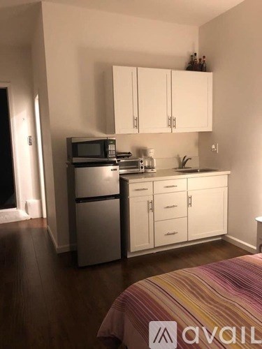 A kitchen with white cabinets and a striped bedspread.