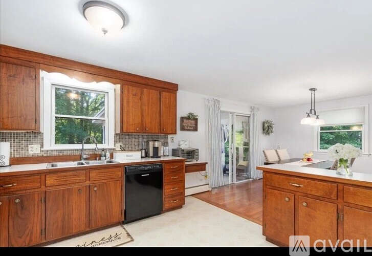 A kitchen with wooden cabinets and a black dishwasher.
