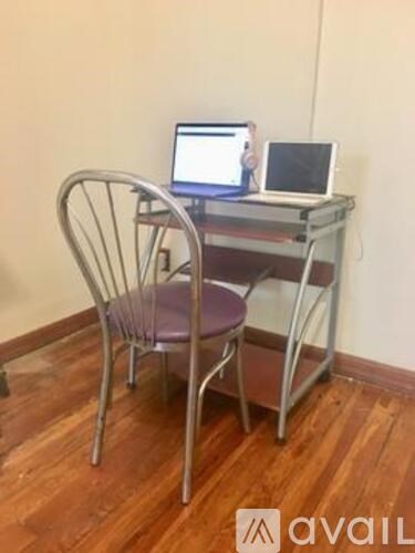 A laptop and a tablet are on a metal computer desk with a chair.