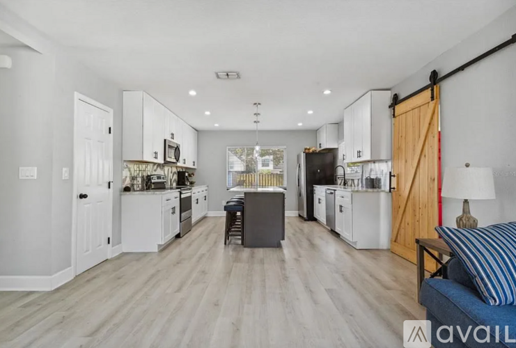 A modern kitchen with white cabinets and a wooden floor.