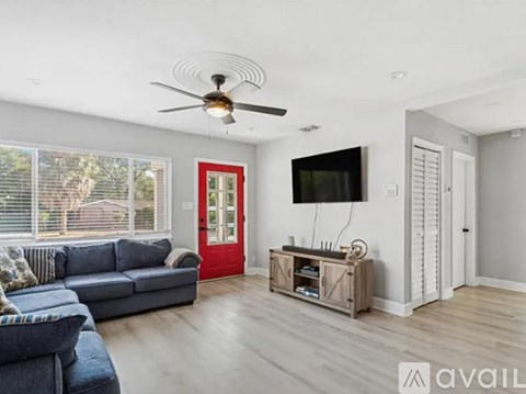 A living room with a grey couch and a red door.