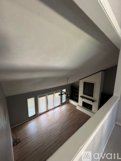 A living room with a television and a row of windows.