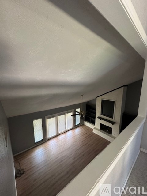 A living room with a television and a row of windows.