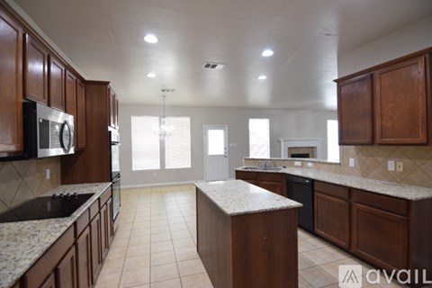 A kitchen with brown cabinets and granite countertops.