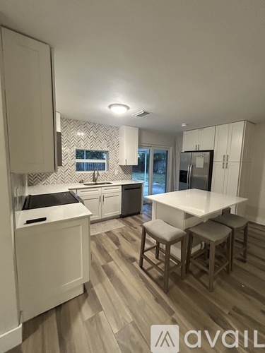 A kitchen with white cabinets and a wooden floor.