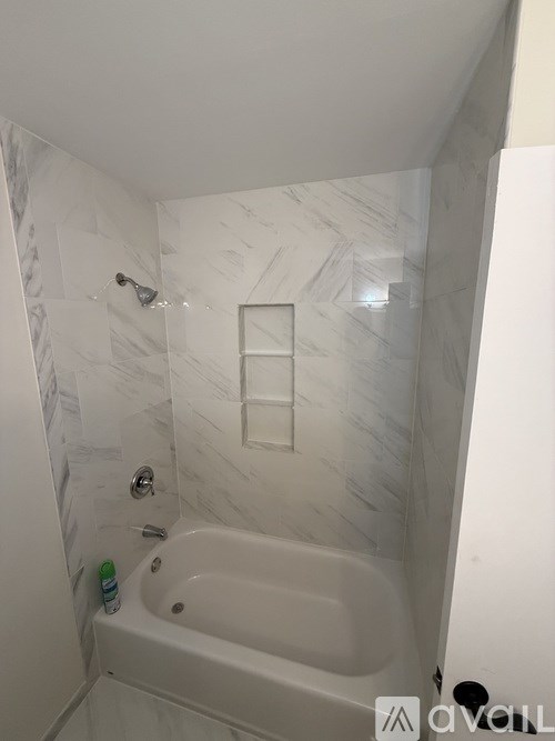 A white bathroom with a marble wall and a white bathtub.