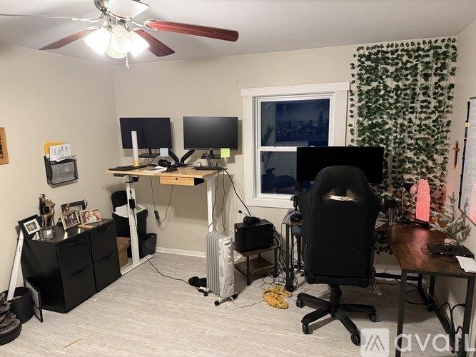 A room with a desk, computer, and a fan.