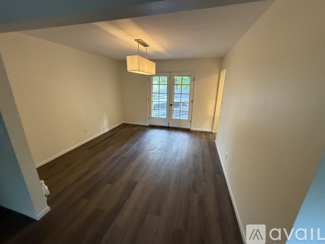 A room with wooden floors and a window with a view of trees.