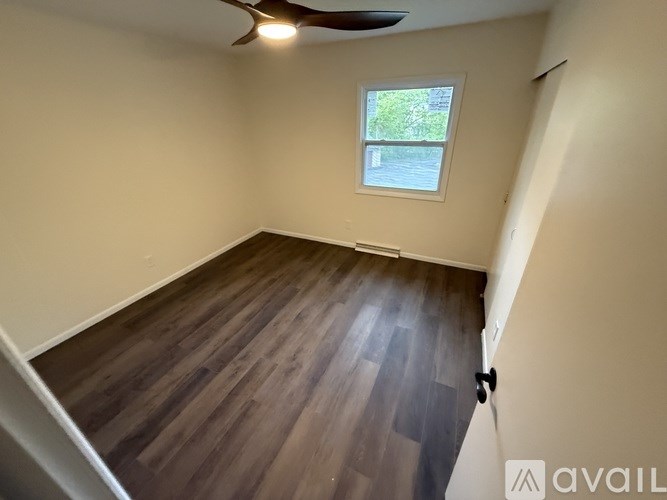A room with wooden flooring and a ceiling fan.