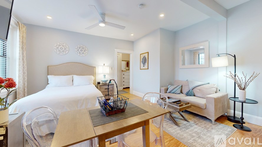 A well-lit bedroom with a bed, a couch, and a table.