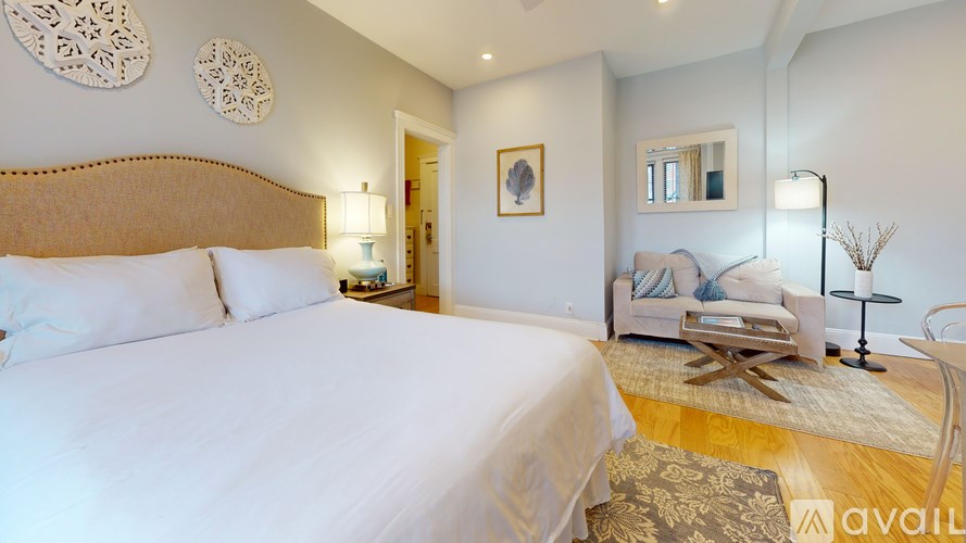 A bedroom with a large bed and a couch in the background.
