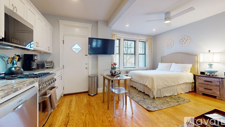 A well-lit bedroom with a bed, nightstand, and a television in the corner.