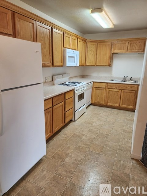 A kitchen with wooden cabinets and a white fridge.