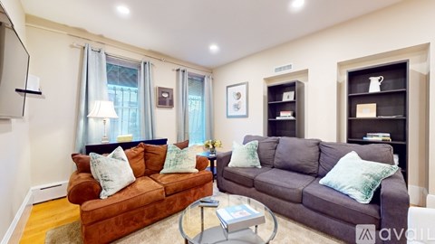 A living room with a brown couch and a glass coffee table.