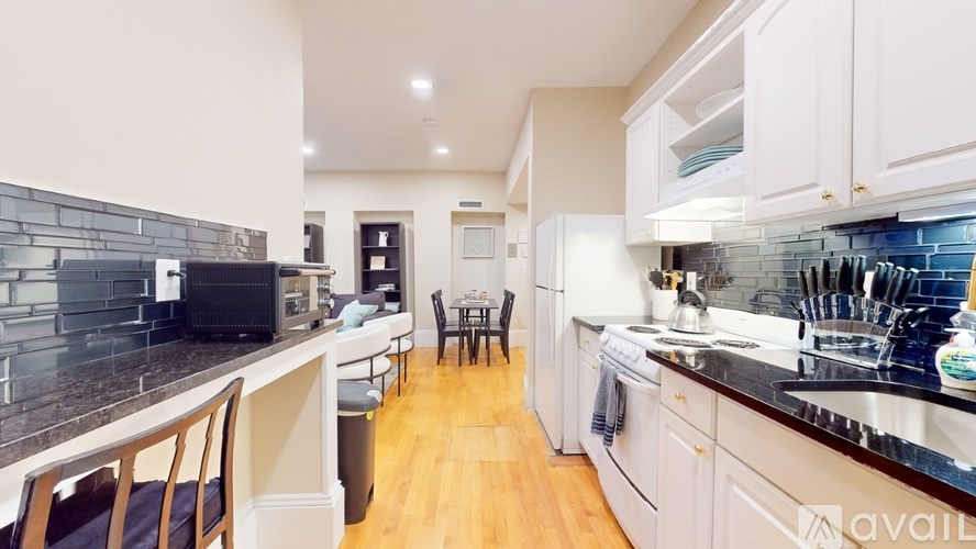 A kitchen with a black counter top and white cabinets.