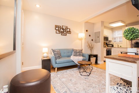 A living room with a blue couch and a brown ottoman.