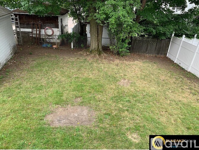 A backyard with a white fence and a tree.