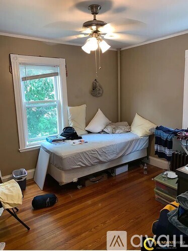 A bedroom with a bed, a window, and a ceiling fan.