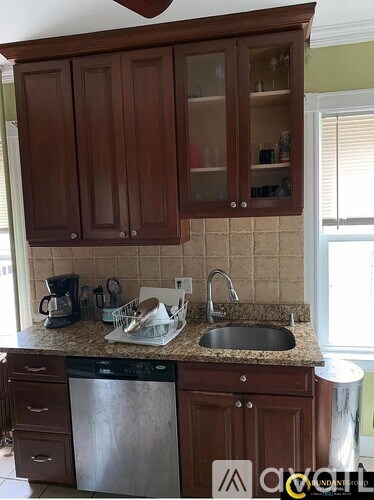 A kitchen with brown cabinets and a black dishwasher.