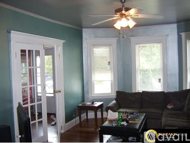 A living room with a couch, a ceiling fan, and a television.