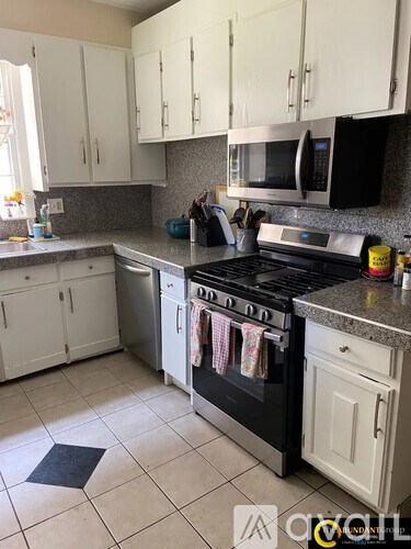 A kitchen with a black stove top oven and white cabinets.