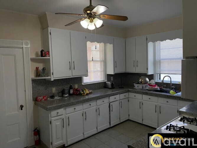 A kitchen with white cabinets and a fan on the ceiling.