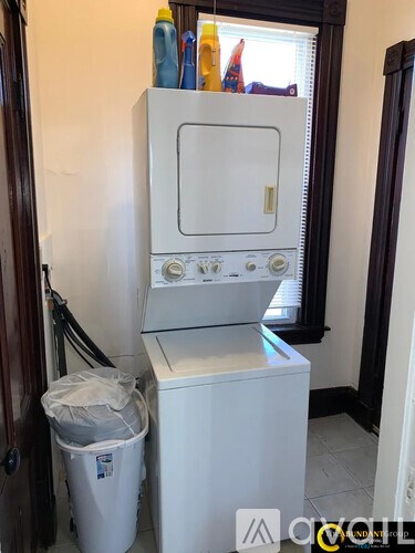 A white dishwasher is in a narrow space between a door and a wall.