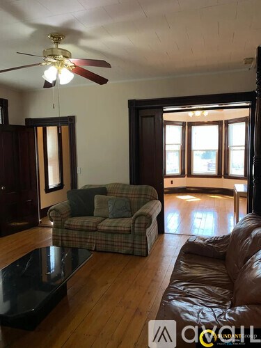 A living room with a brown couch and a plaid chair.