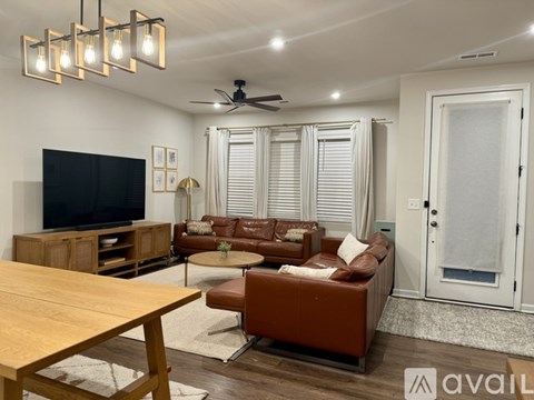 A living room with a brown leather couch and a wooden table.