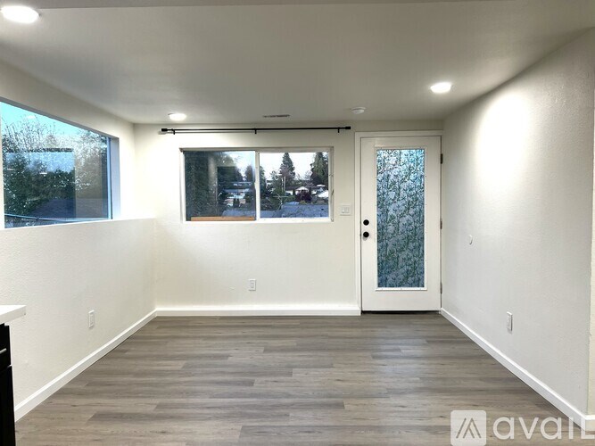 A room with a door and a window showing a view of trees and a house.