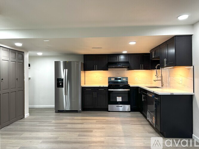 A modern kitchen with black cabinets and stainless steel appliances.