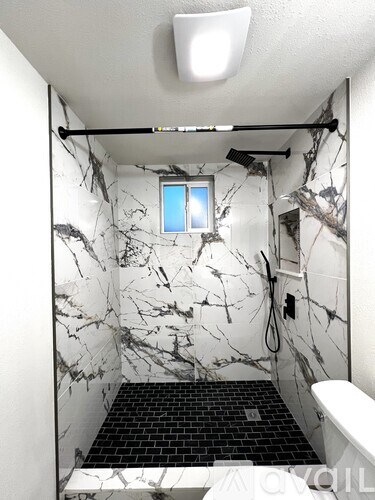 A bathroom with marble wallpaper and a small window.