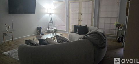 A living room with a grey couch and a television on the wall.