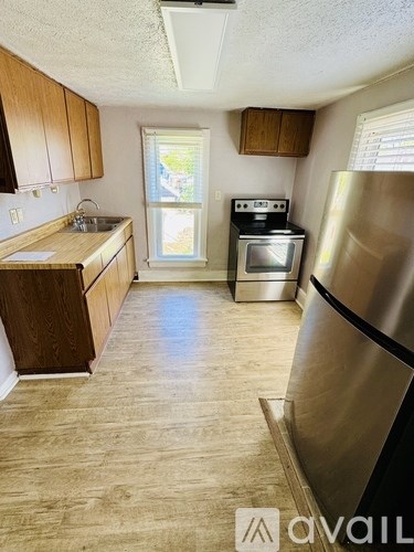 A kitchen with wooden cabinets and a stainless steel refrigerator.