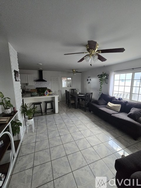 A living room with a black couch and a ceiling fan.