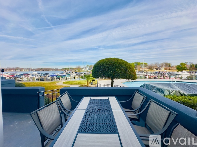 A table and chairs are set up on a balcony with a view of a pool and trees.