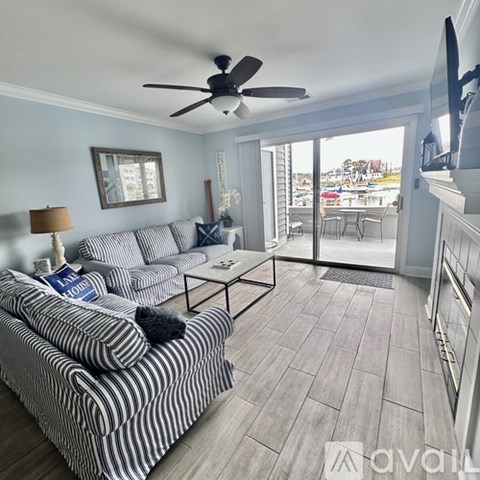 A living room with a striped couch and a ceiling fan.