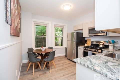 A kitchen with a table and chairs in front of a window.