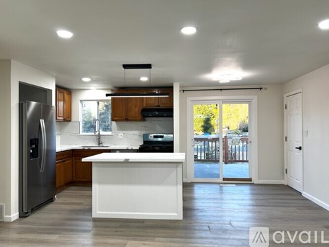 A kitchen with a refrigerator, sink, and stove top oven.