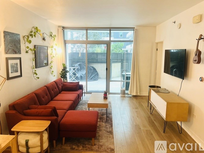 A living room with a red couch and a flat screen TV mounted on the wall.
