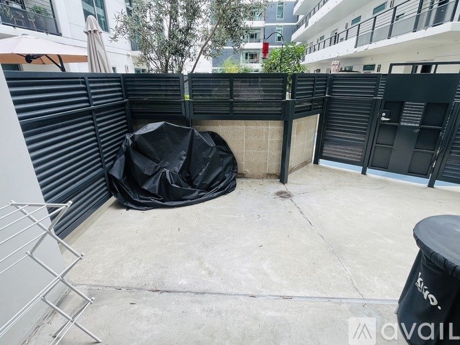 A black tarp is covering a concrete area surrounded by a fence.