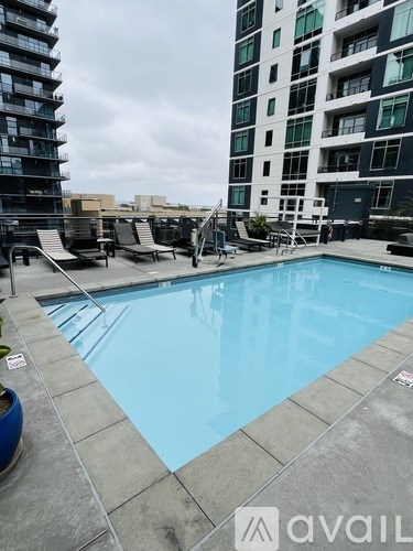 A swimming pool on a rooftop with chairs around it.