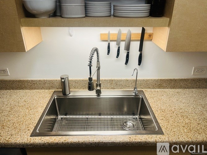 A kitchen sink with a silver faucet and a knife rack above it.