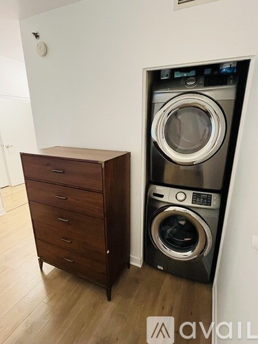 A brown chest of drawers sits next to a wall-mounted washing machine.