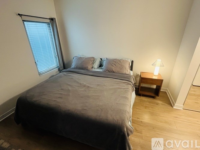 A bedroom with a bed, a nightstand, and a window.