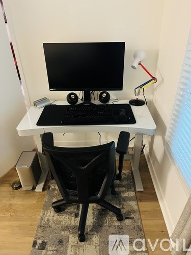 A black and white computer desk with a monitor, keyboard, and mouse.